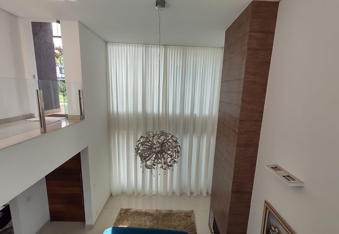 Cortina translúcida em sala com pé-direito duplo: a automação permite controlar a entrada de luz com um comando.